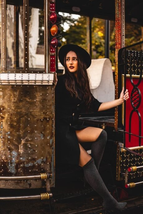 Woman in Black Coat with Black Hat Sitting on Red Vehicle